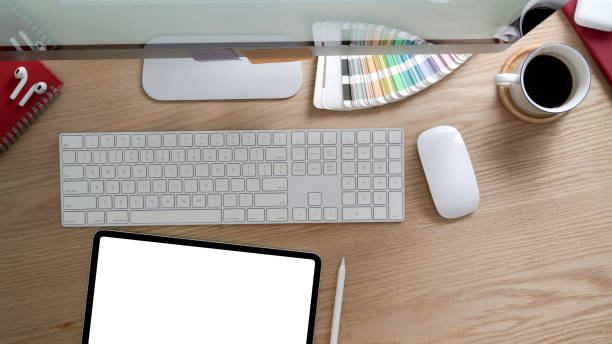 istock Top view of designer workspace with mock up tablet, computer and office supplies on modern rustic desk 1202467116