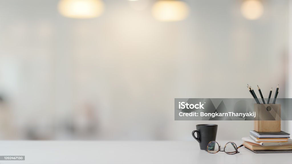 Close up view of workspace with stationery, glasses and coffee cup on white table with blurred background Close up view of simple workspace with copy space, stationery, glasses and coffee cup on white table with blurred background Desk Stock Photo