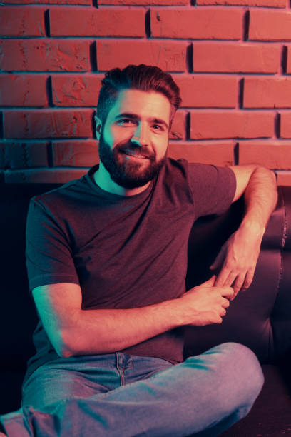 istock Bearded young man sitting on a leather couch 1202469419