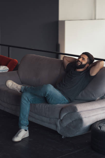 istock Young man sitting relaxing on the couch 1202469446