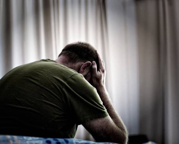 vista trasera del hombre deprimido o enfermo, la cabeza en las manos - men mental illness loss despair fotografías e imágenes de stock