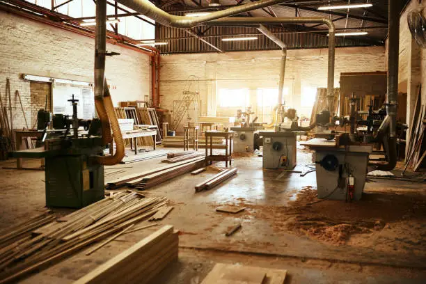 Still life shot of the machinery and piles of wood inside a carpentry workshop