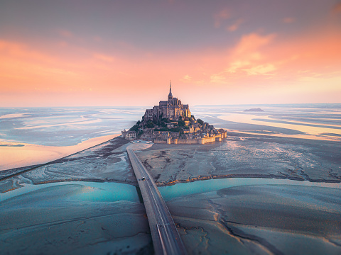 Aerial view of famous Mont Saint Michel tidal island and jetty bridge at a beautiful  sunrise time in Normandy, Northern France