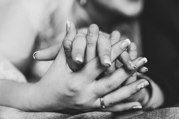 istock Closeup on two young lovers holding hands. Black and white photo. 1202472304