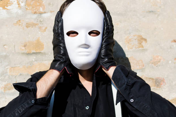 istock Man holding white mask on his face and looking at camera. 1202473675