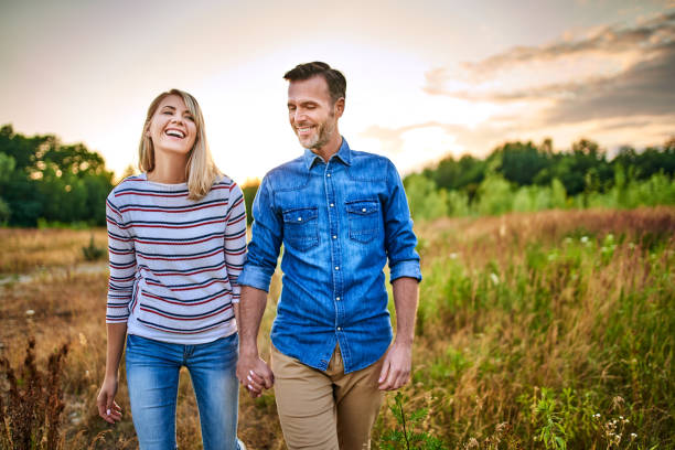 istock Smiling couple walking through meadow on sunny day and holding hands 1202473730
