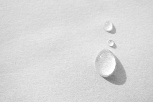 Water drop on white paper textured background with copy space and selective focus, close-up. Concept moisturizing macro, top view stock photo