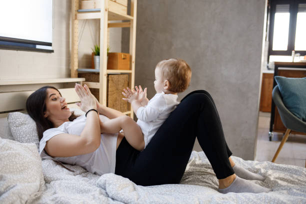 madre che gioca a battere le mani con il suo bambino a letto - battere le mani esprimere a gesti foto e immagini stock