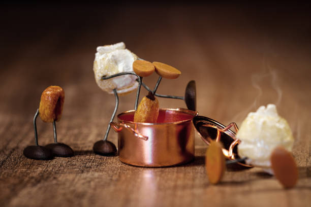 Funny scene with popcorn figures on a wooden table, black background, copper pot with popping maize or corn it