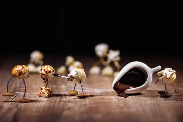 funny popcorn figures are glacing or dipping others with chocolate, chocolate icing on party snacks