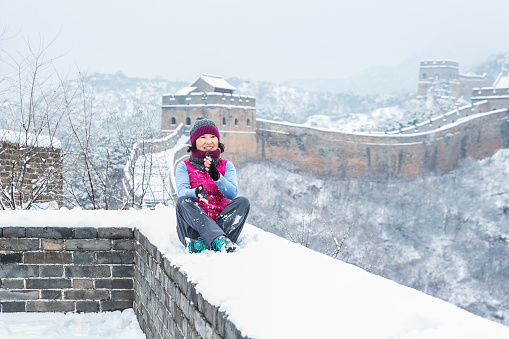 A Chinese woman on the Great Wall of China with snowflakes