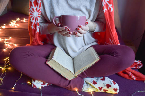 istock Woman indoors holding a coffee mug and reading a book 1202478628