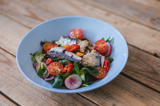 Mediterranean cuisine, simple anchovy salad with vegetables on plate, close up, no people