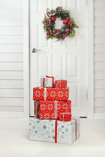 Christmas gift boxes delivered to vintage house door with wreath decoration