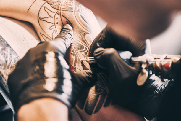 Tattoo Artist making a tattoo on a shoulder in tattoo studio