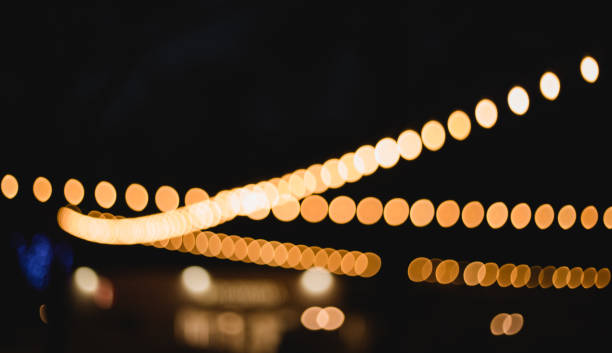 istock Decorative outdoor string lights at night time, Defocused Background, night city life backdrop, party time with Yellow bokeh balls 1202483420