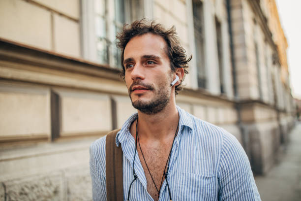 homem hipster na cidade ouvindo música em fones de ouvido sem fio - men smiling headphones individuality - fotografias e filmes do acervo
