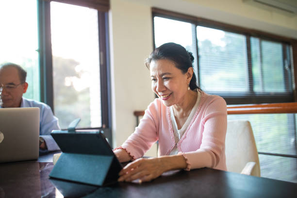 istock Senior woman sitting at table and using digital tablet at home 1202484929