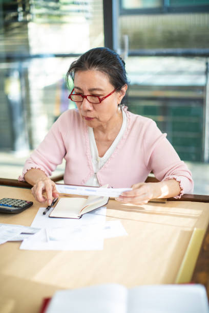 istock Senior Taiwanese looking at papers at home 1202485741