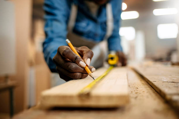vista ravvicinata delle laboriose mani di una donna falegname professionista che lavora con un righello e fa segni sul legno - carpenters pencil foto e immagini stock