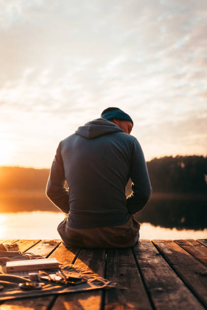 istock Man sits on a pier on the lake 1202486783
