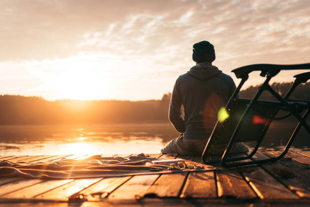 istock Man sits on a pier on the lake 1202486810
