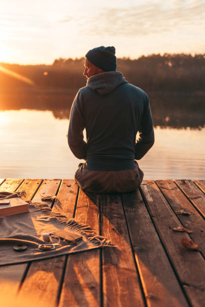 istock Man sits on a pier on the lake 1202486855