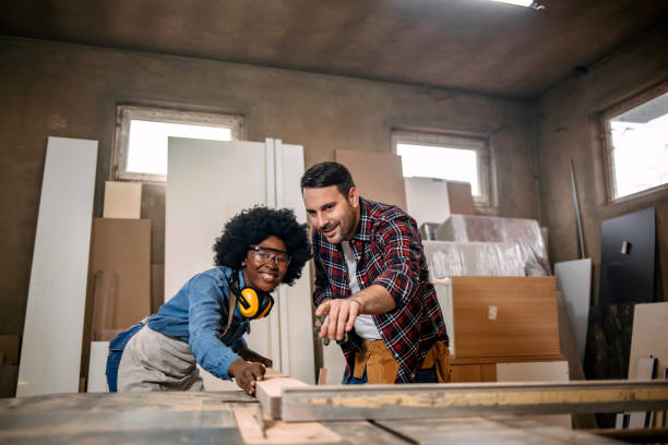 istock Couple of young carpenters using a circular saw 1202487147