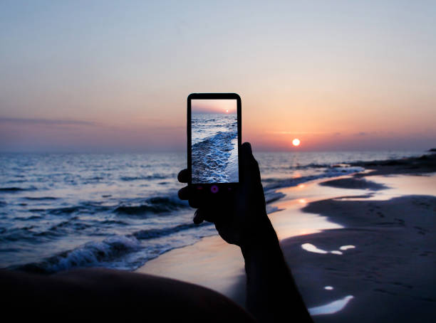 istock Man is taking a sunset photo on the cell phone 1202487489