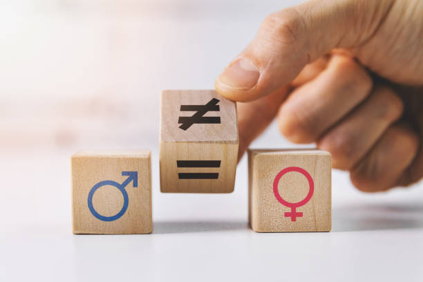 gender equality and discrimination concept - hand putting wooden blocks with symbols - uneven imagens e fotografias de stock