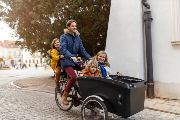 ung familj njuter av att umgås och cykla i en lastcykel - parents children cargo bike bildbanksfoton och bilder