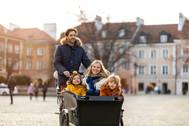 ung familj njuter av att umgås och cykla i en lastcykel - parents children cargo bike bildbanksfoton och bilder