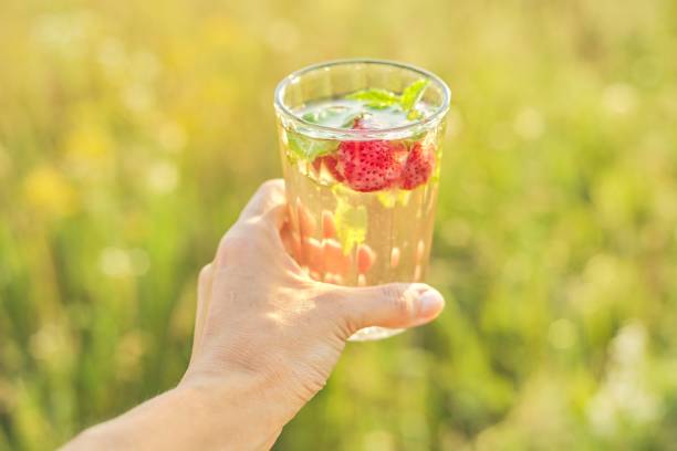 istock Summer natural refreshing drink with mint strawberries in woman hand 1202492411