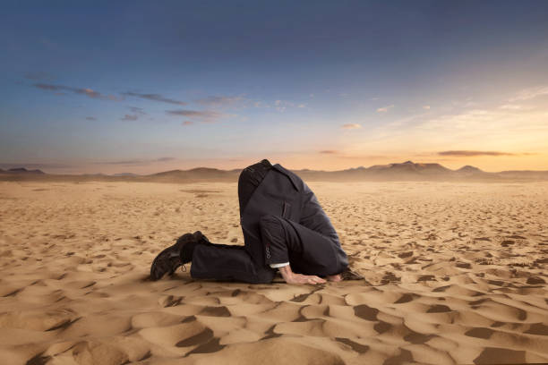 uomo d'affari desparato che nasconde la testa nella sabbia - suicide men business humor foto e immagini stock