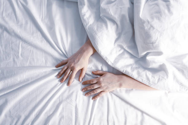 istock Insomnia concept. Woman's hands on white sheet. 1202499464
