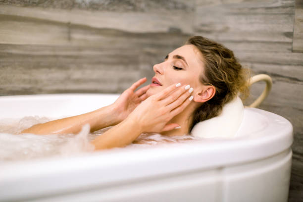 Close up of beautiful young lady relaxing at thermal bath in a beauty center, touching face, smiling Close up of beautiful young lady relaxing at thermal bath in a beauty center, touching face, smiling. woman hot shower stock pictures, royalty-free photos & images