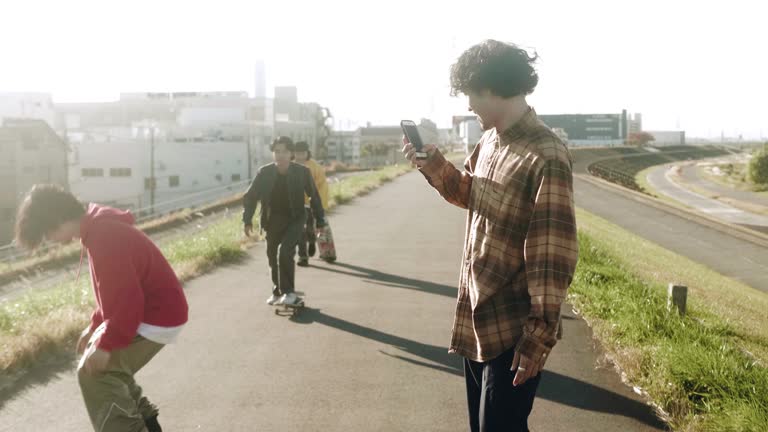 Long video series of Japanese teenage skateboarder friends chilling, skating, filming, using smart phone and eating pizza in the skatepark. Clips are in normal and slow motion speed.