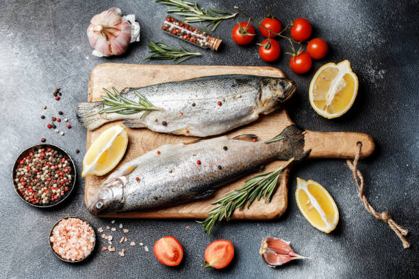어두운 돌 배경에 요리 향신료와 재료와 신선한 강 송어 - trout prepared fish whole grilled 뉴스 사진 이미지