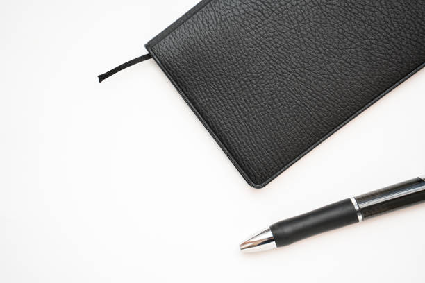 istock Black notebook and ballpoint pen on White background 1202507122