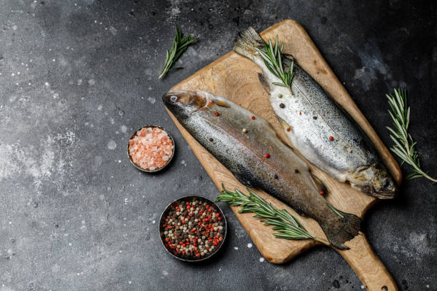 istock Fresh river trout with spices and ingredient for cooking on dark stone background 1202507954