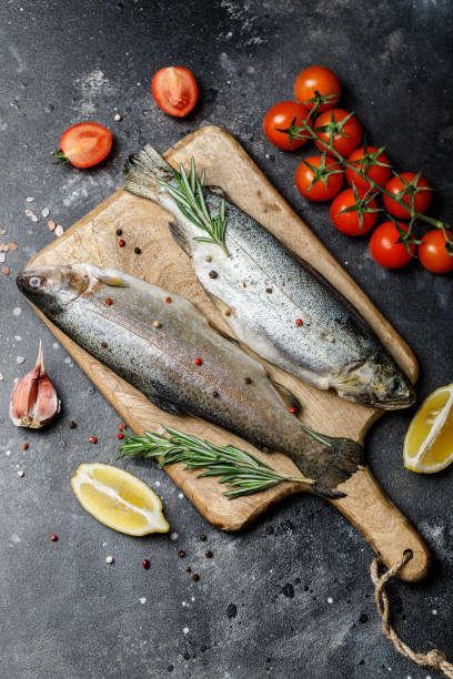 istock Fresh river trout with spices and ingredient for cooking on dark stone background 1202508030