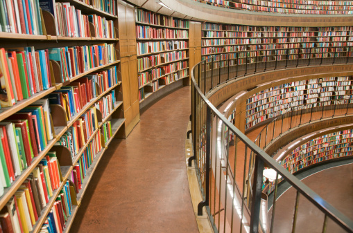 Halifax Central Library bookshelves near entrance with stairs to second floor in background.