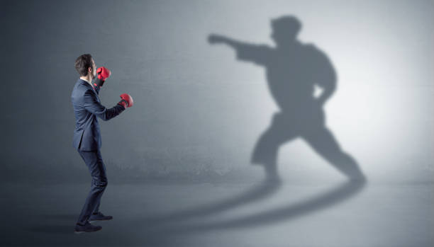 istock Young businessman fighting with his shadow 1202509238