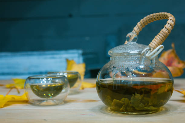 istock Autumn glass cup of tea and fallen maple leaves 1202510874