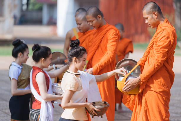 Laotian people making offerings to Buddhist monks during alms giving ceremony in Luang Prabang Laos Luang Prabang, Laos - August 21 2016: Laotian people making offerings to Buddhist monks during traditional morning alms giving ceremony alms stock pictures, royalty-free photos & images