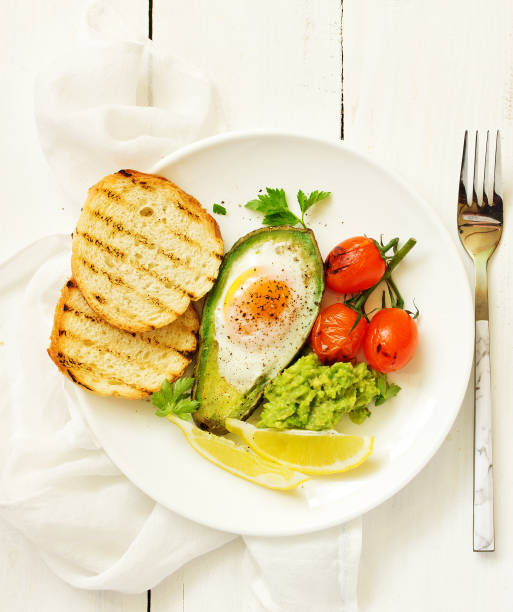 istock Fried eggs in avocado with guacamole sauce. Breakfast. Selective focus 1202513132