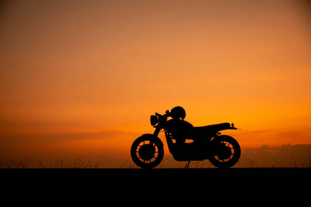 夕焼けの背景を持つオートバイの駐車場のシルエット - motorcycle biker riding motorcycle racing ストックフォトと画像