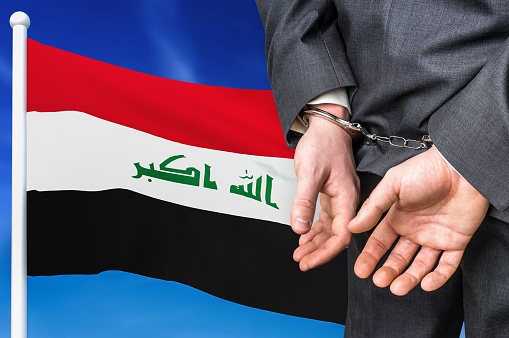 Prisons and corruption in Iraq. Businessman with handcuffs on national flag background.