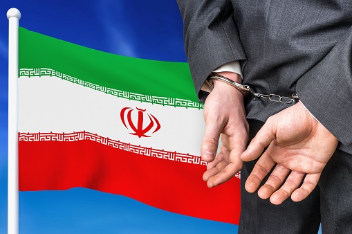 Prisons and corruption in Iran. Businessman with handcuffs on national flag background.