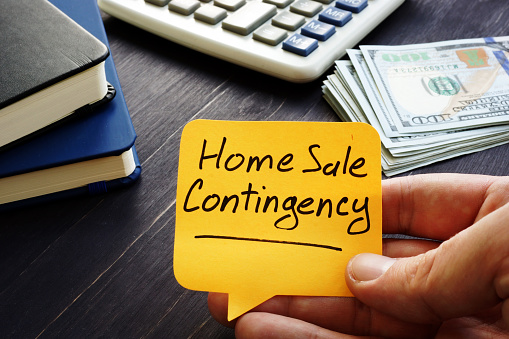 Real Estate Agent holds home sale contingency memo sign.